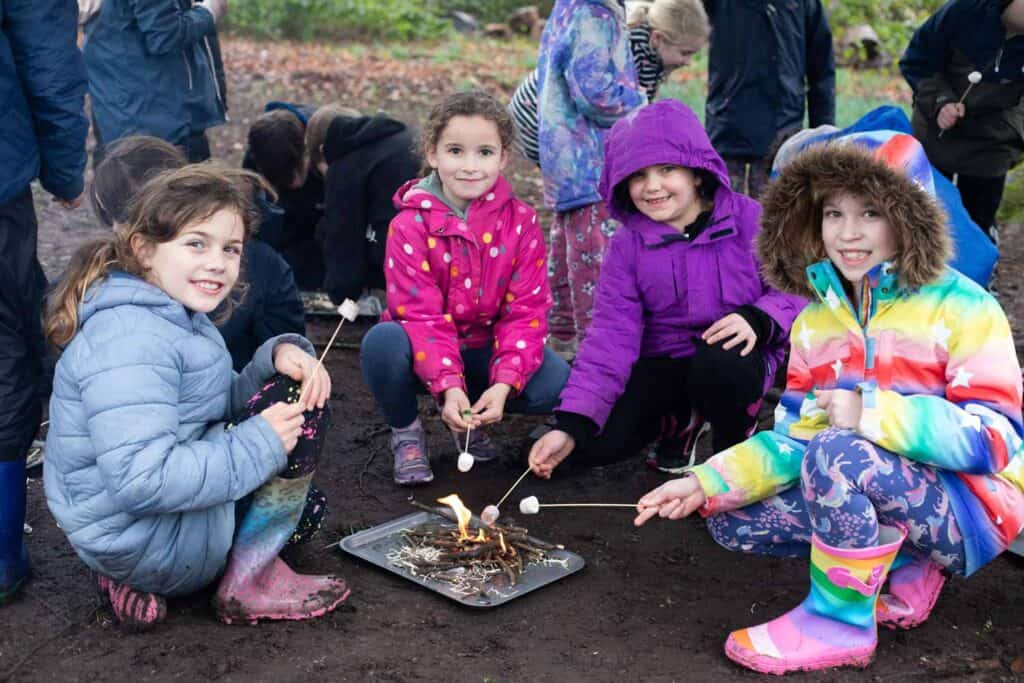 Children building a campfire together in the forest at our holiday club, enjoying outdoor activities