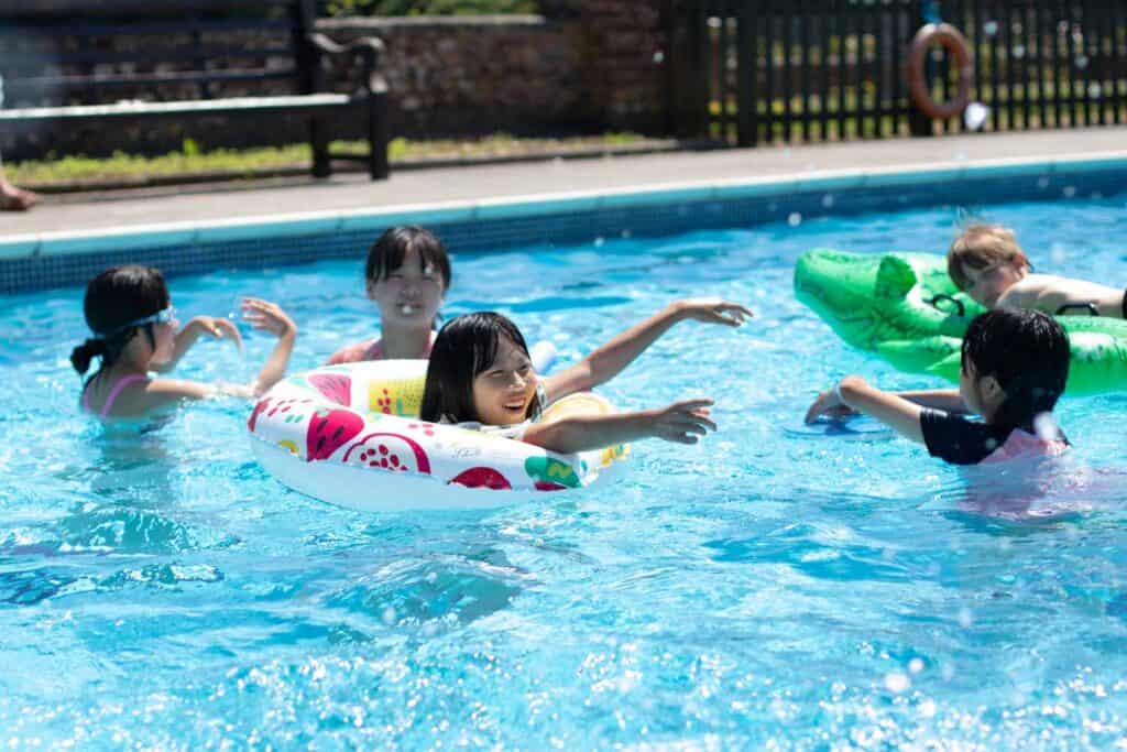 Children swimming in pool with the inflatables at our holiday club, enjoying outdoor activities