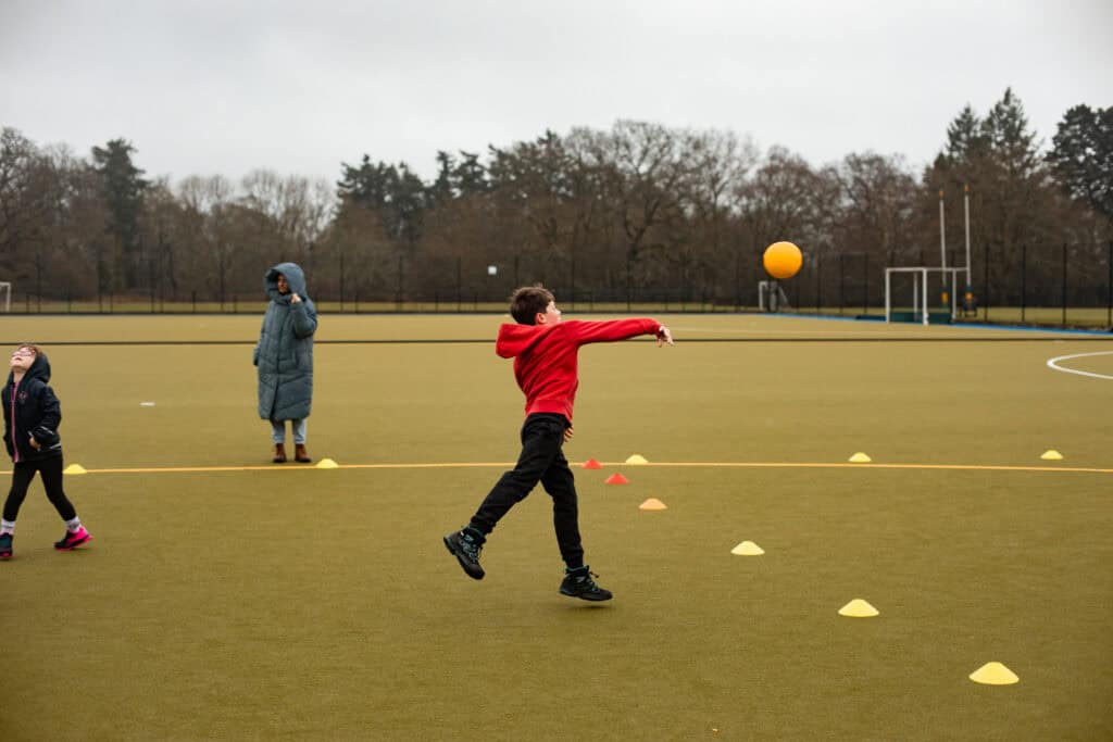 A boy aged 6-10 throwing a dodgeball to the opposing team. 