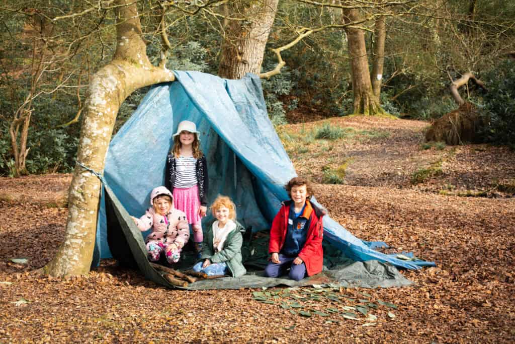 A group of kids at our day camps sat in their shelter they built together